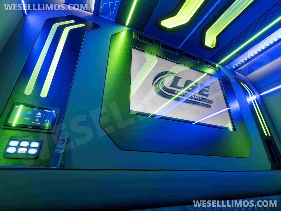Interior of a limo with a large screen, neon green and blue lighting.
