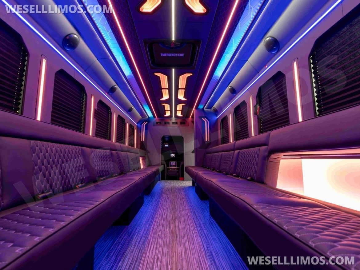 Interior of a party bus with purple leather seating, neon lights, and wooden floors.