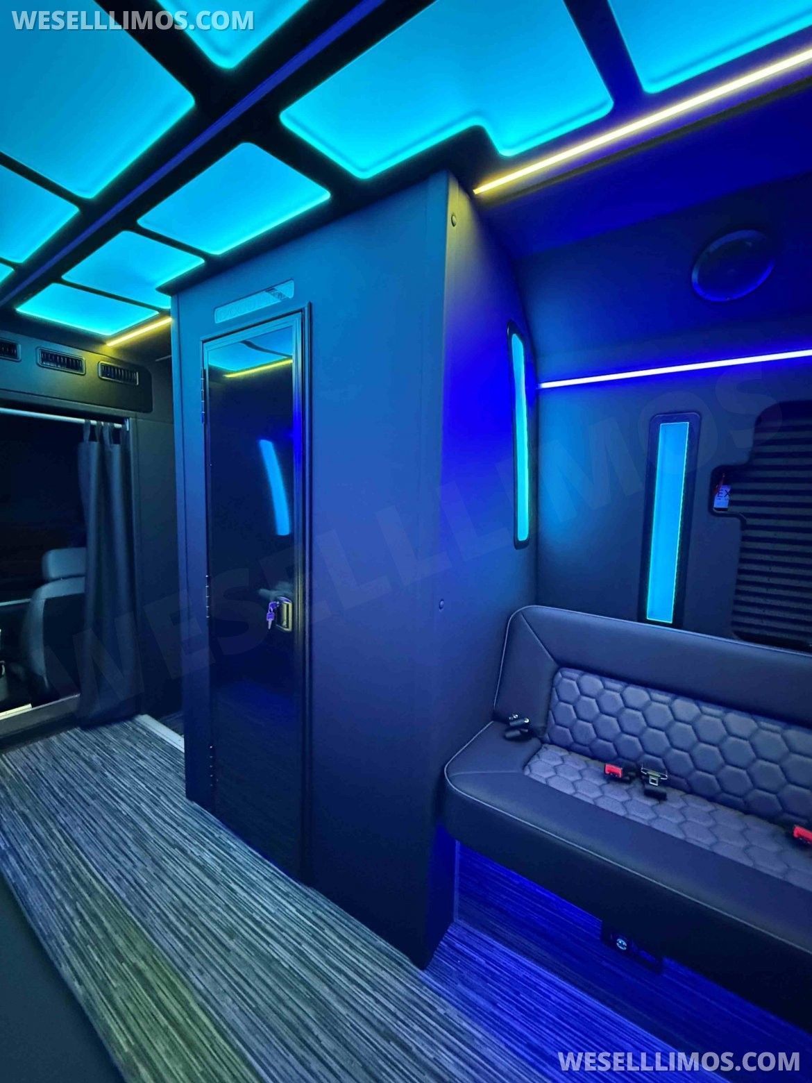 Inside a black van with blue neon lighting, a seating area, and a mirrored wall.