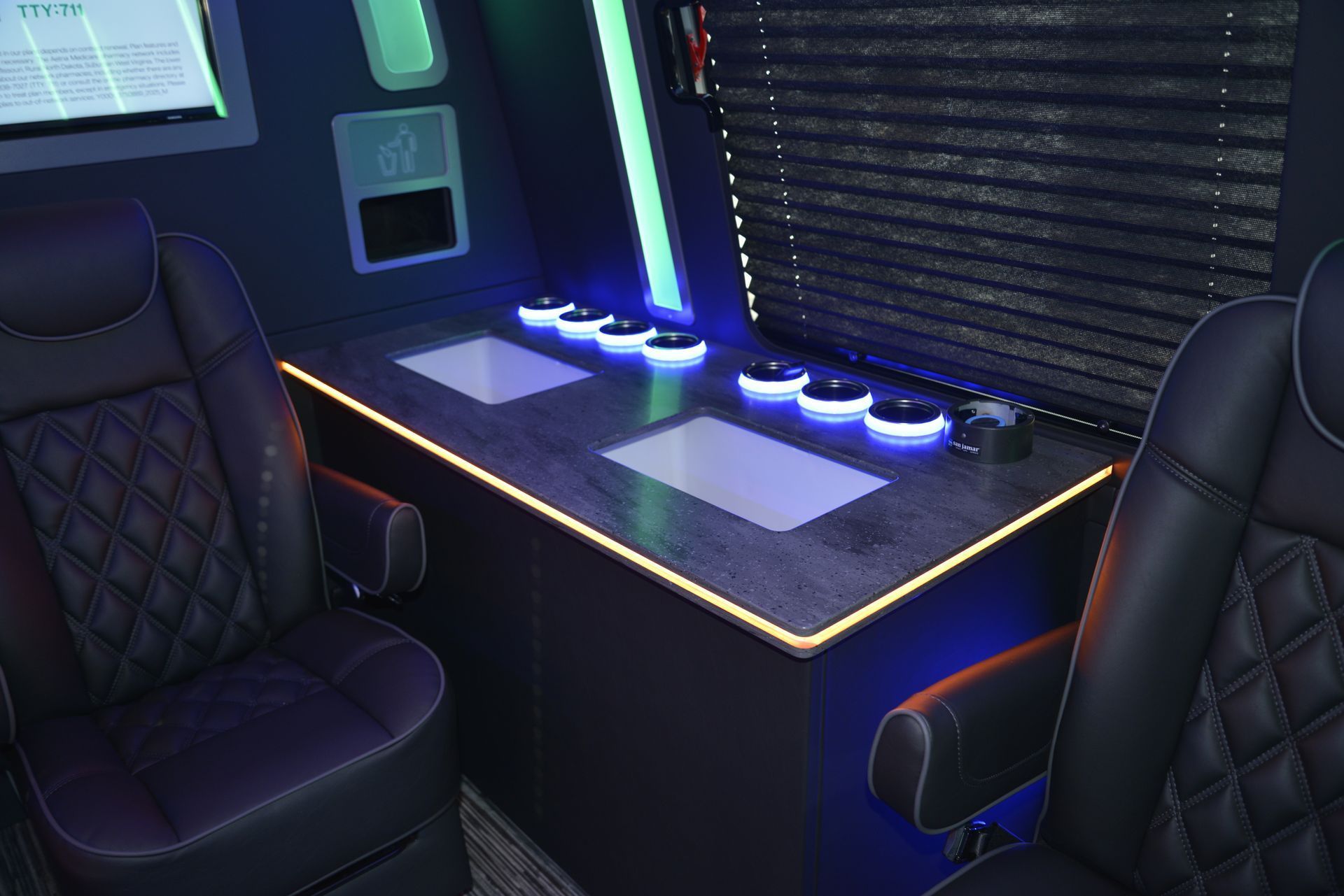 Interior of a dark vehicle with two black quilted leather seats. A control panel has buttons and glowing blue lights.