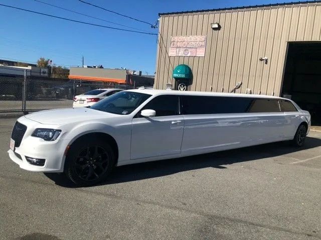 A white stretch limousine parked outside a tan industrial building on a sunny day