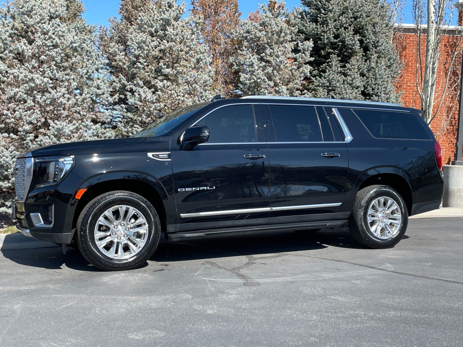 Black GMC Yukon Denali parked on a paved lot with trees in the background.