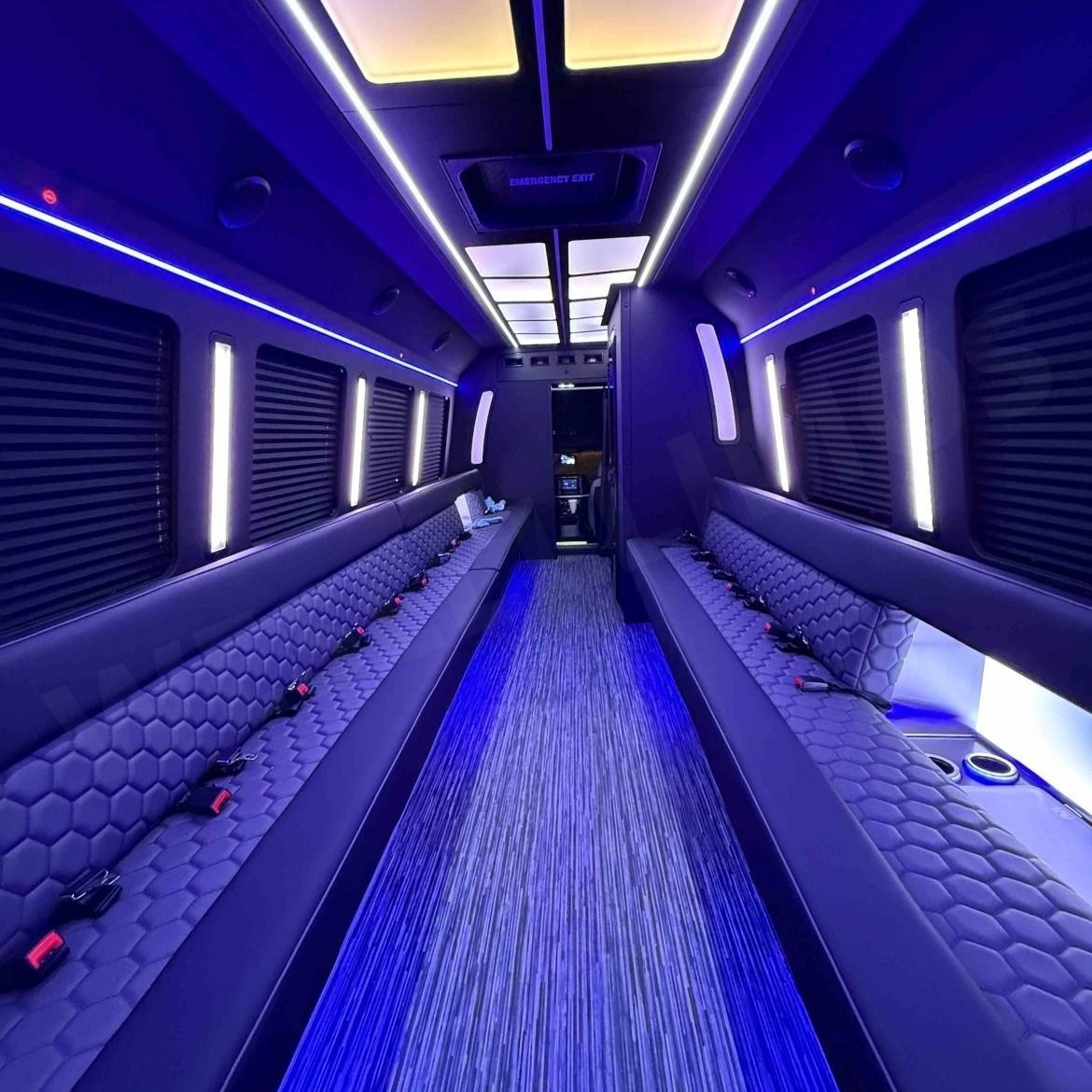 Interior of a party bus with blue LED lights, quilted seats, and a center aisle.