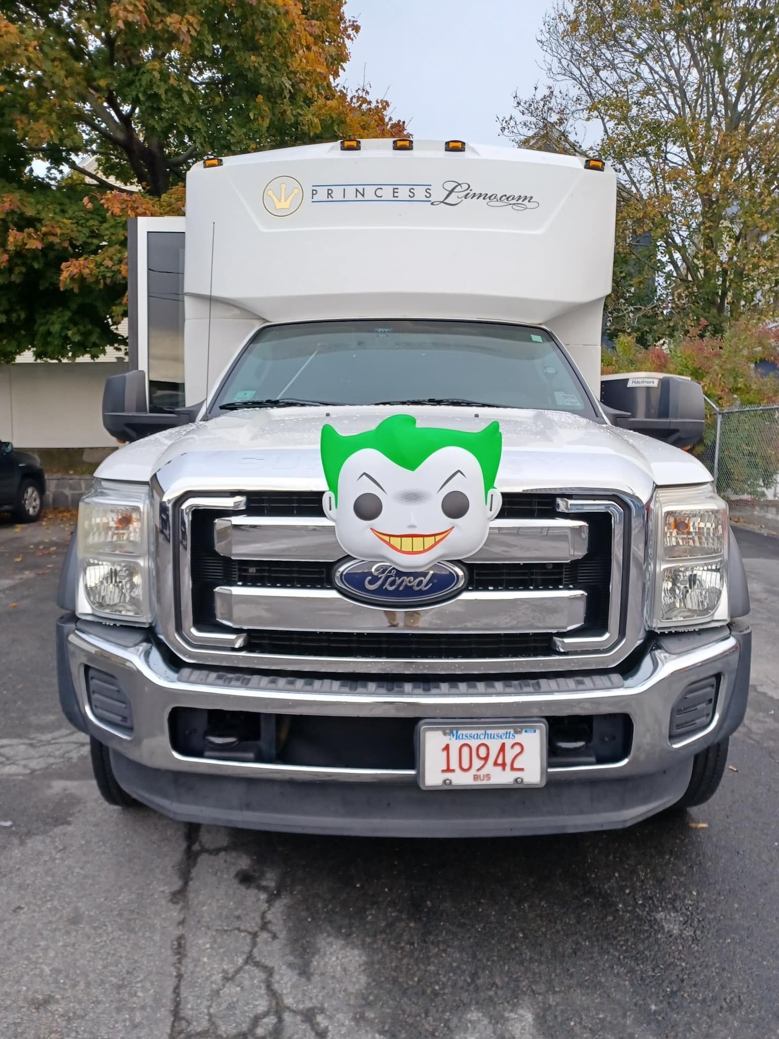 Silver truck with a Joker Funko Pop figure on the grill, parked outdoors.