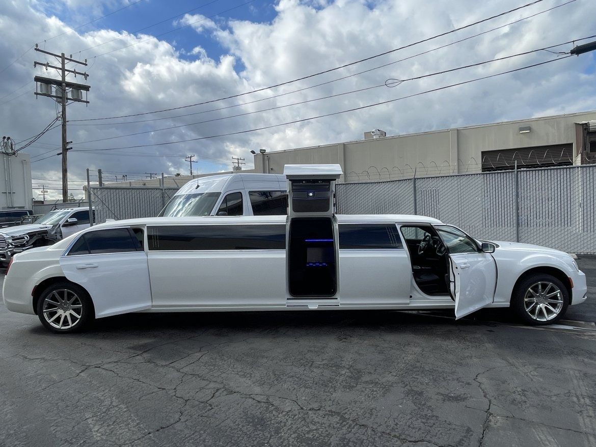 White limousine with doors open, parked on a street.