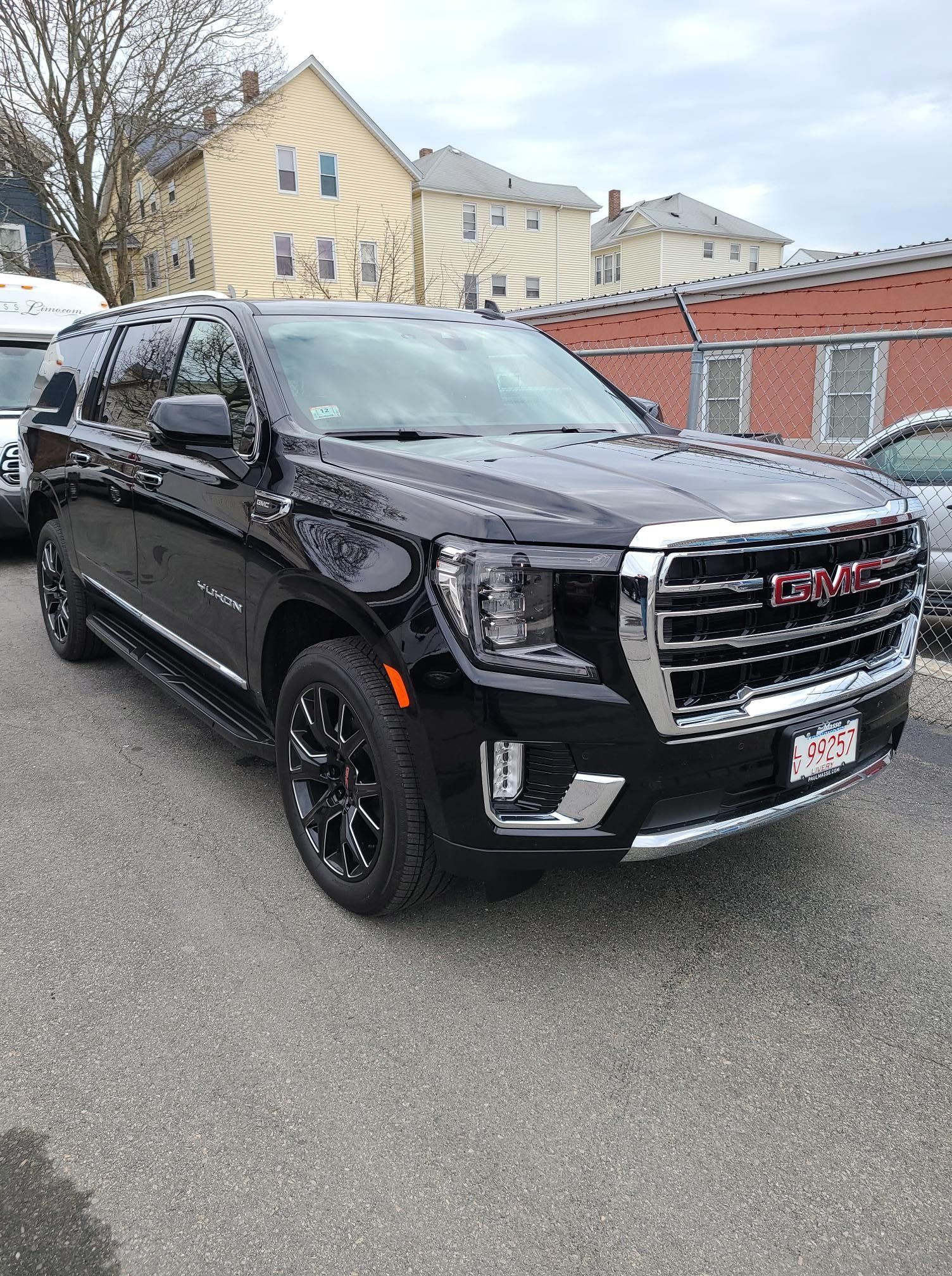 Black GMC Yukon SUV parked on pavement in front of buildings.