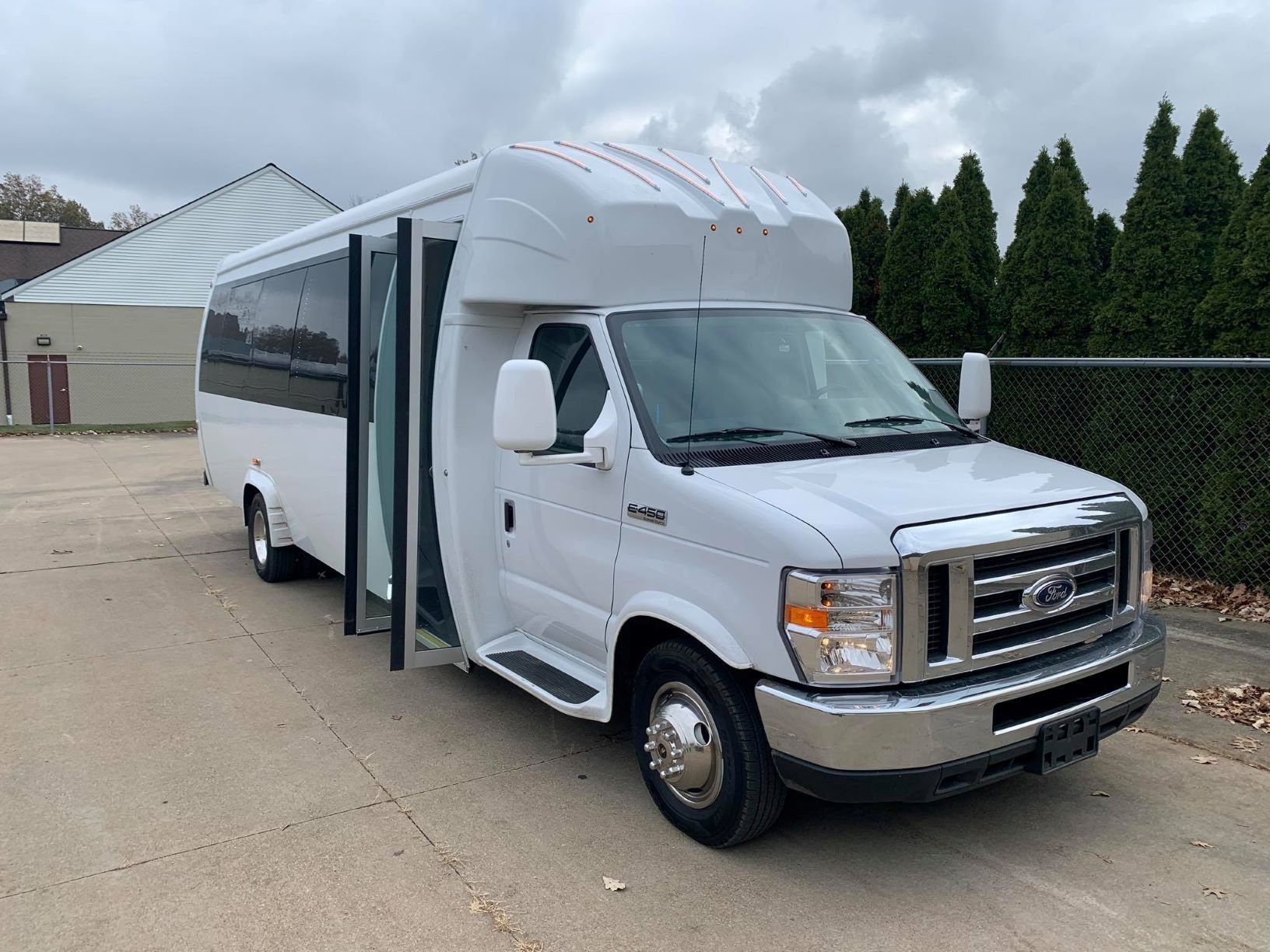 White passenger bus with the door open, parked on concrete.