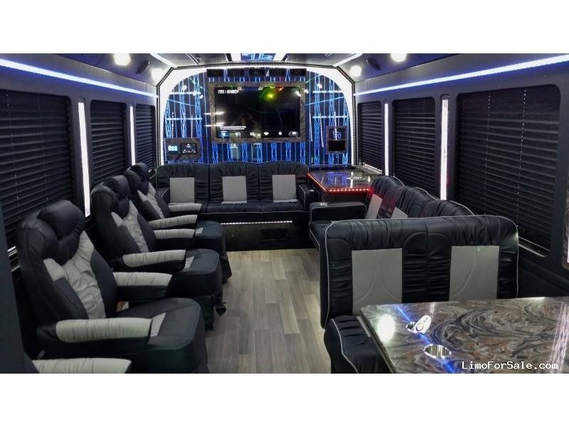 Interior of a luxury party bus with seating, TV, and table with marble top.