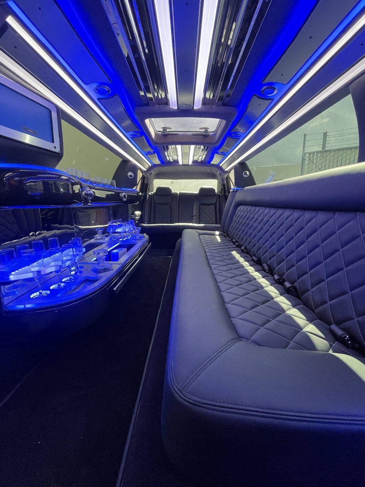Interior of a limousine with blue lights and black leather seating.