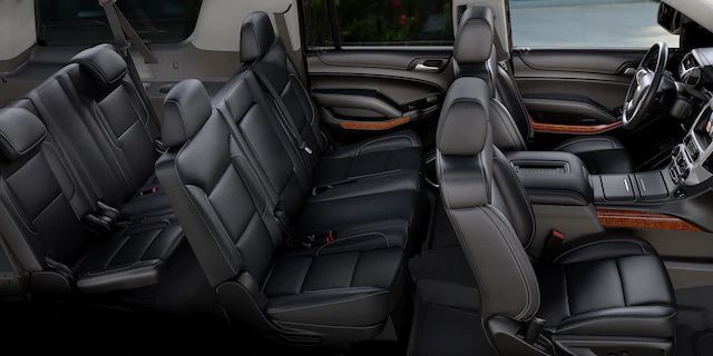 Black leather interior of a vehicle with three rows of seating.