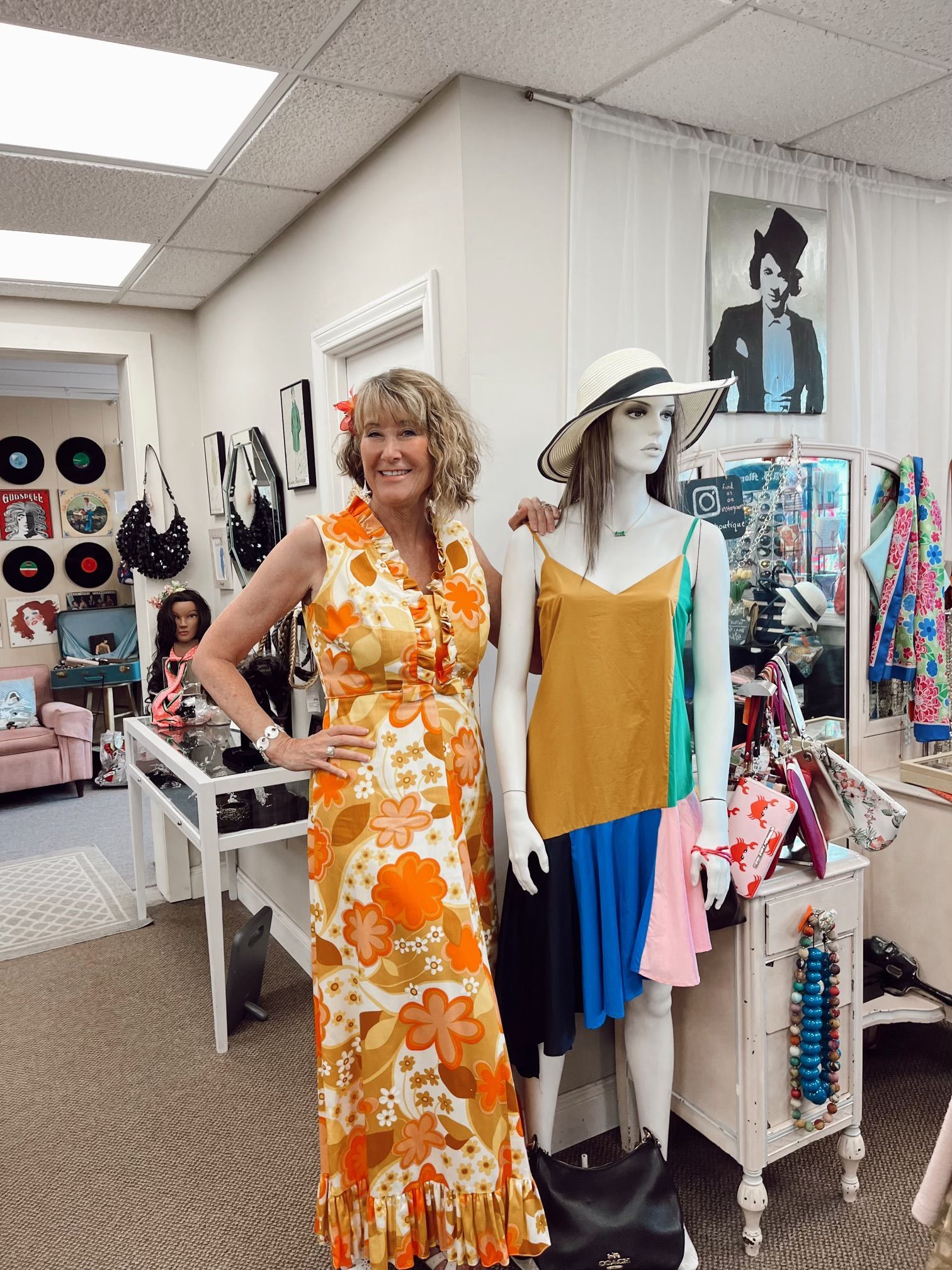 a woman in a dress is standing next to a mannequin in a store