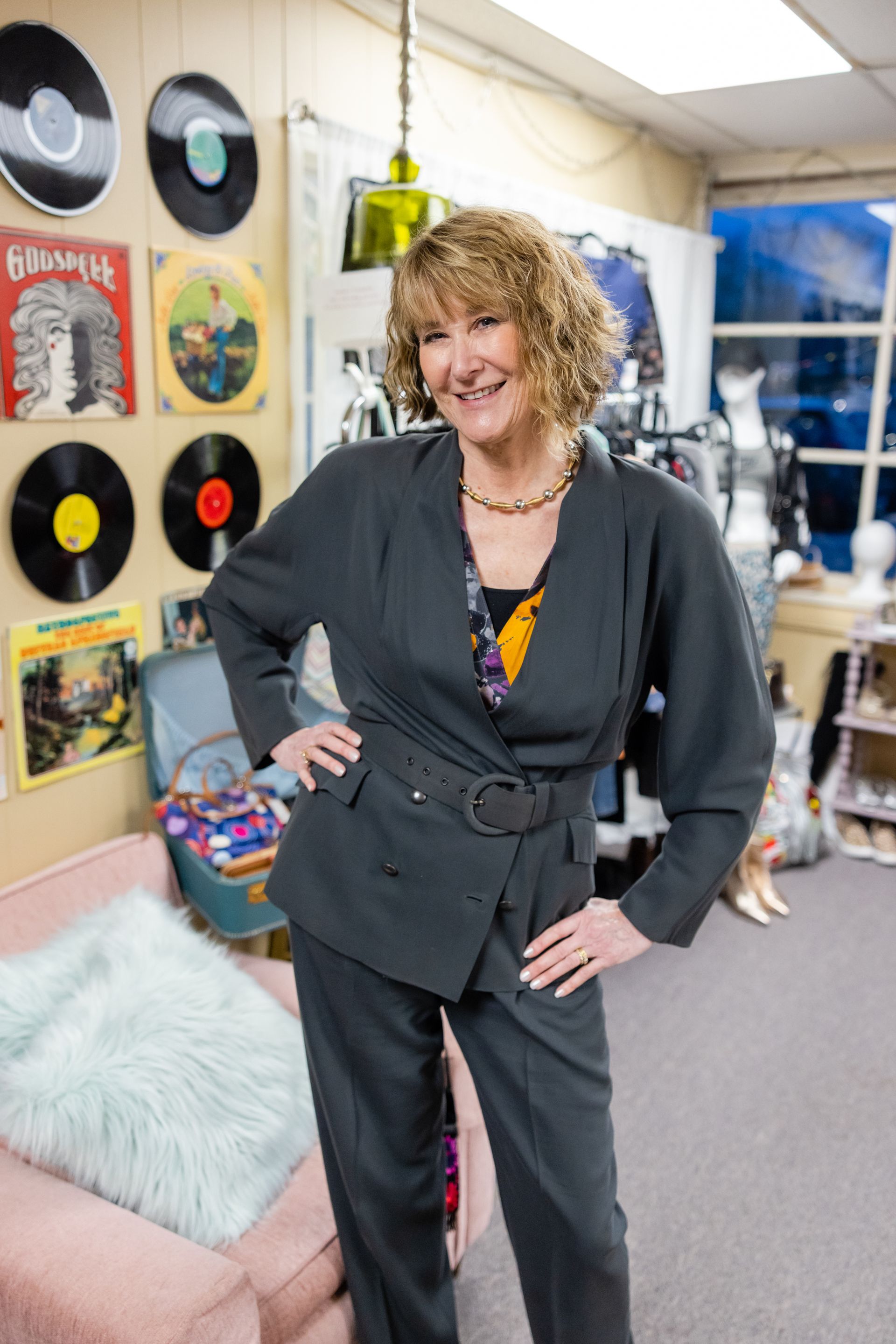 a woman in a suit is standing in a room with records on the wall
