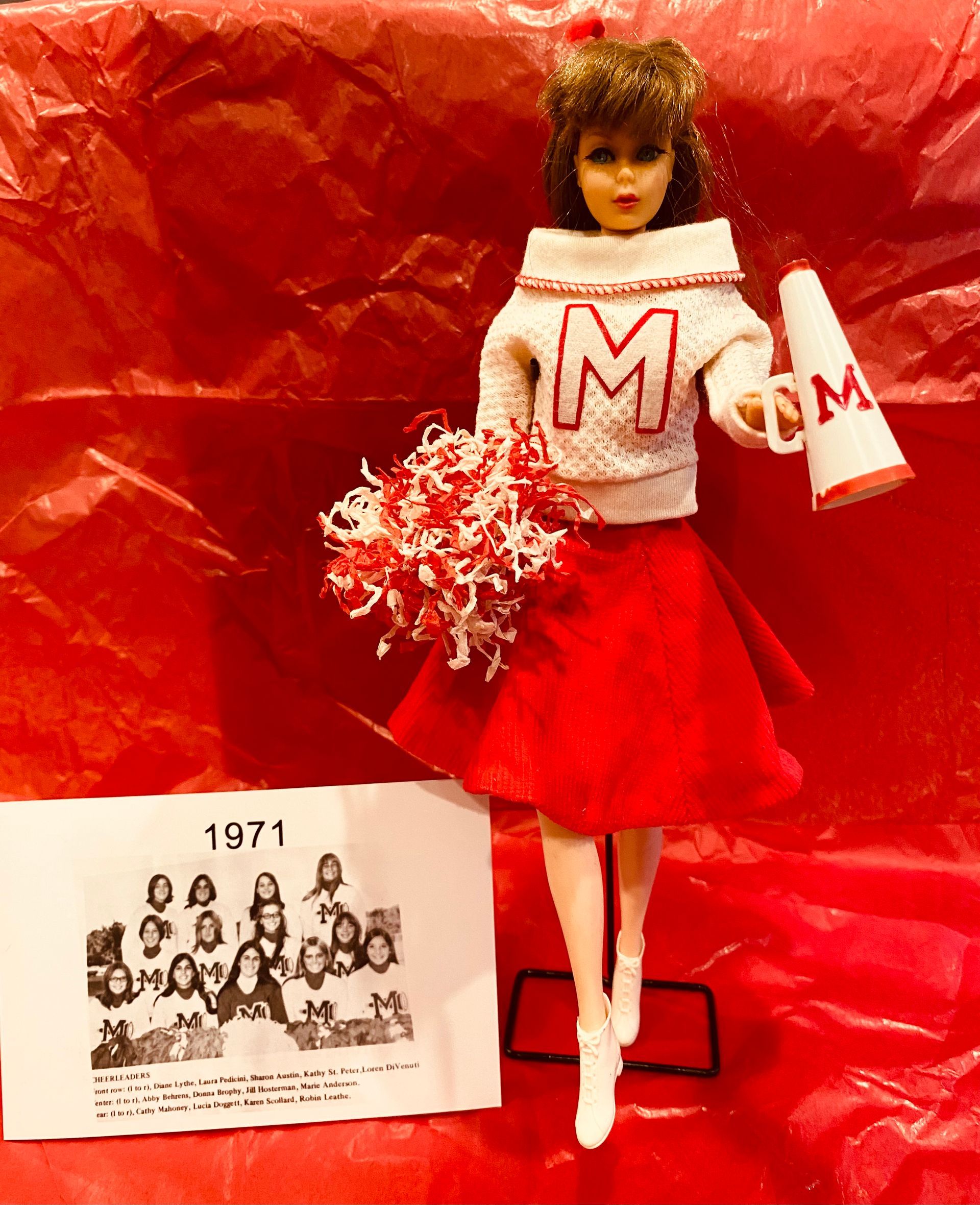 a doll wearing a sweater with the letter m on it