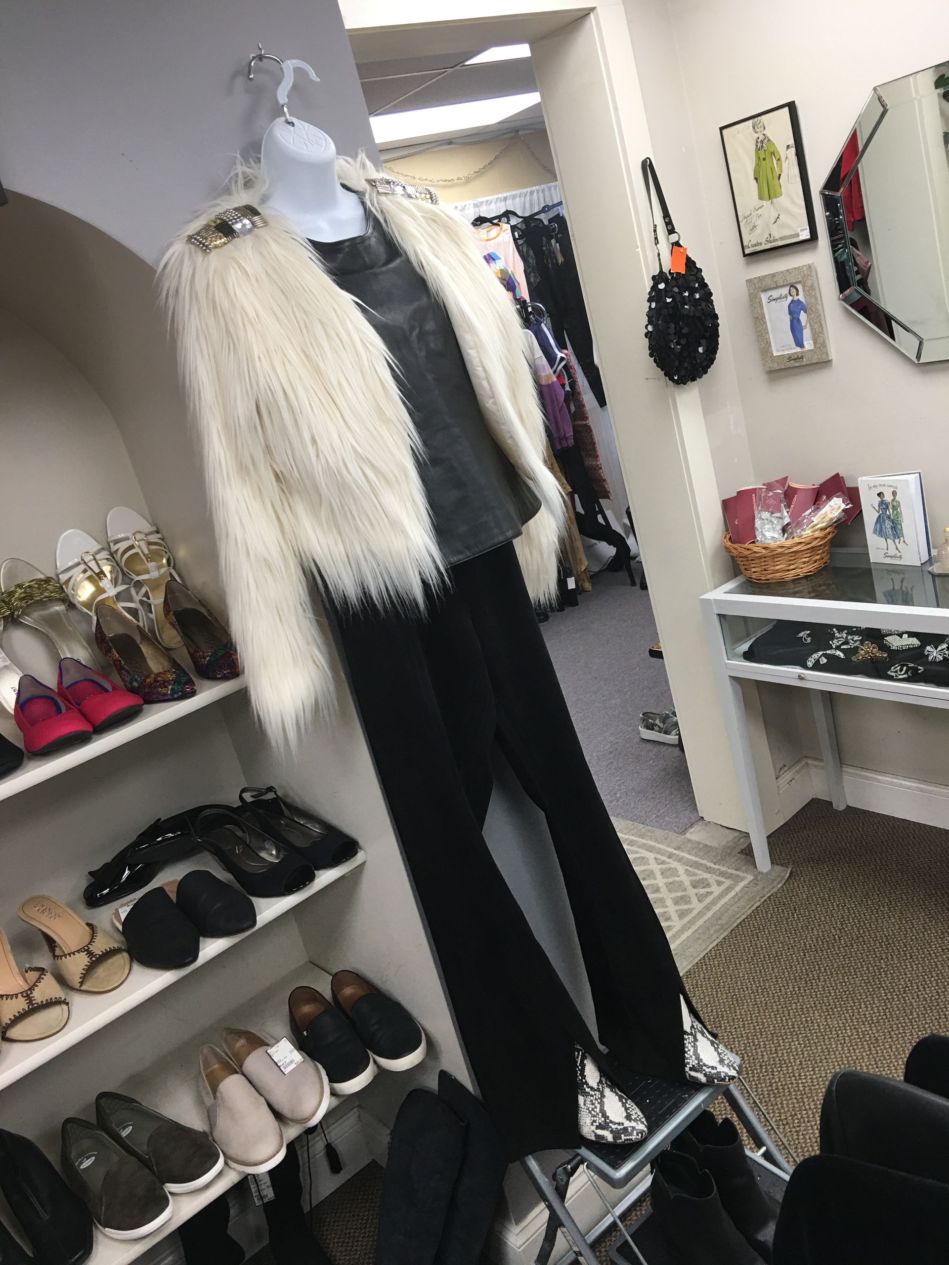 a mannequin is wearing a white fur coat and black pants