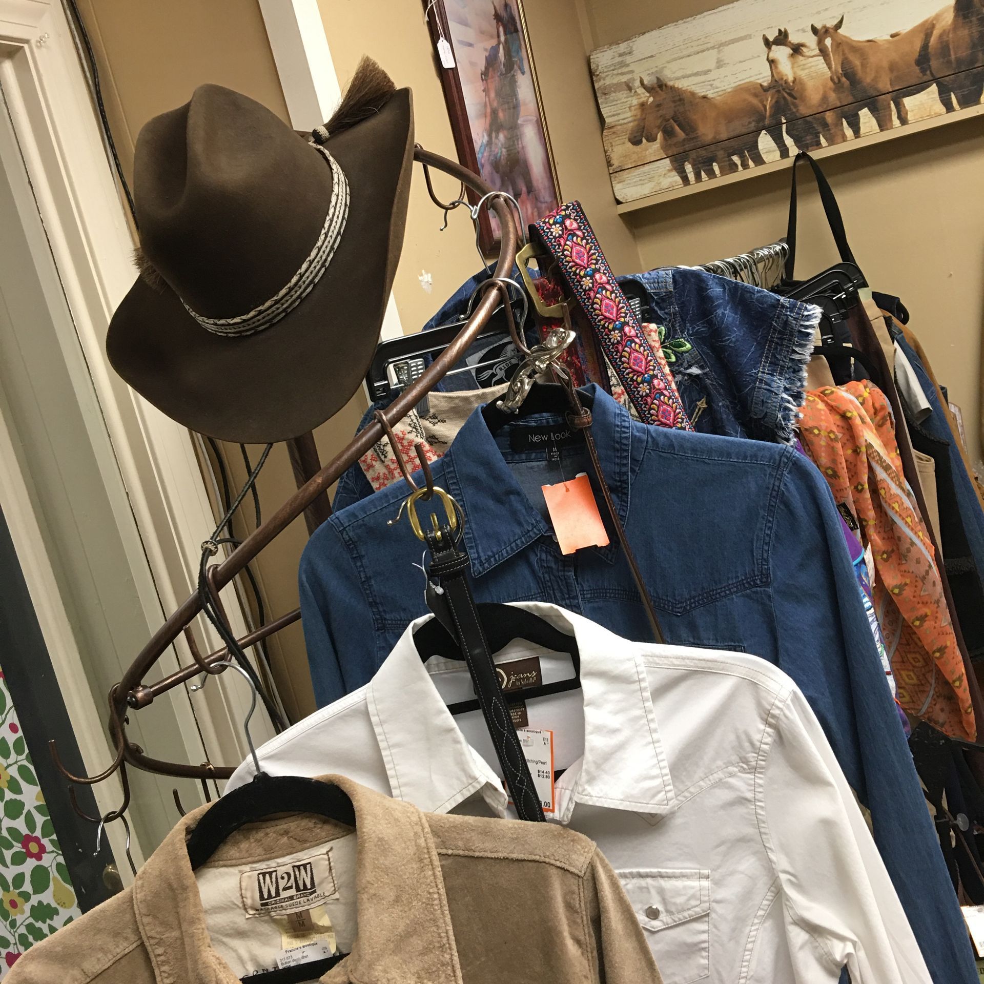 a cowboy hat is hanging on a clothes rack