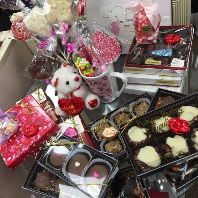 a table filled with boxes of candy and a teddy bear with a heart on it