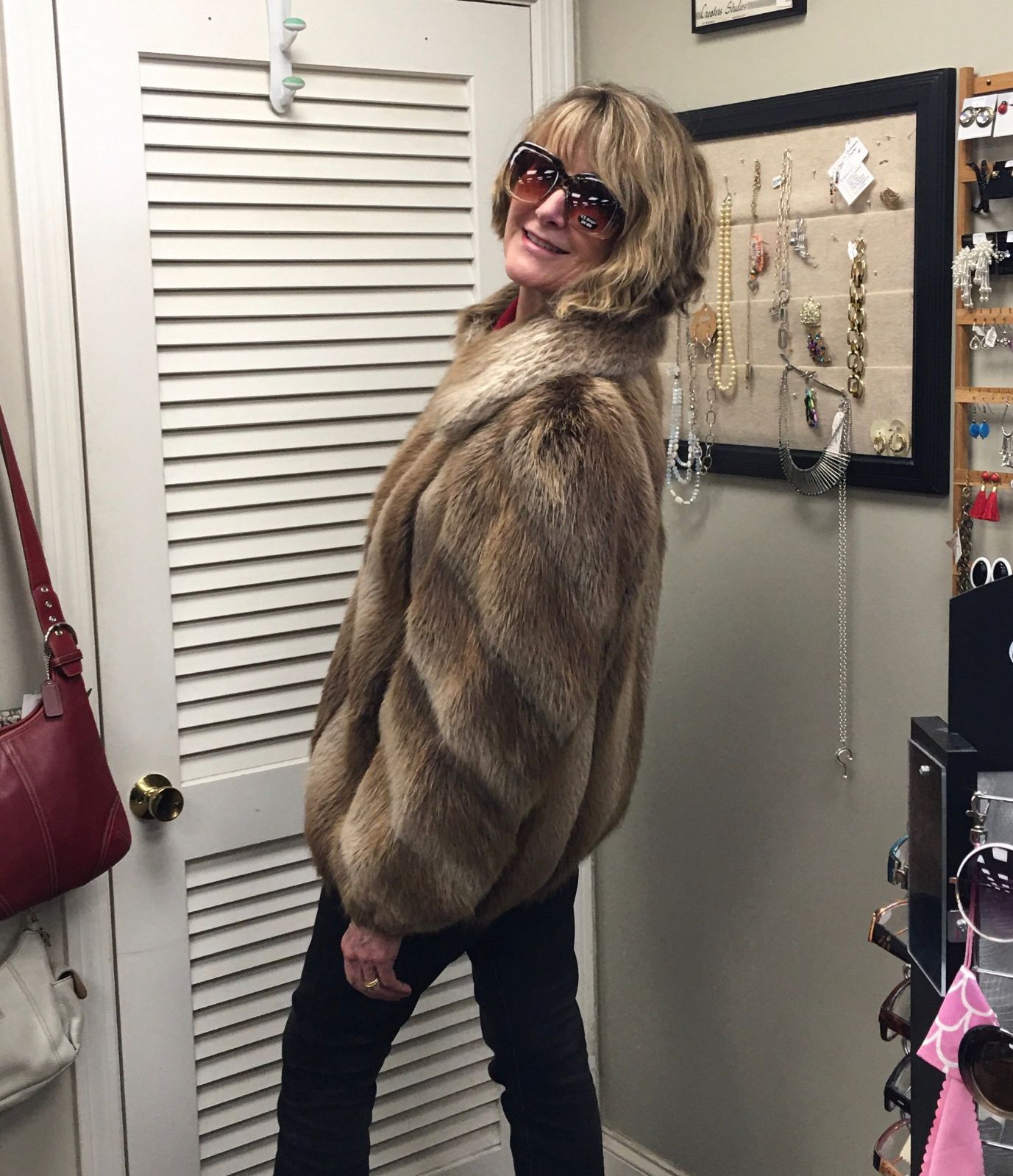a woman wearing a fur coat and sunglasses is standing in front of a door