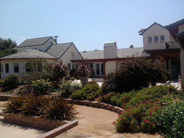 Buildings with white walls, gray tile roofs, and a lush garden in front.