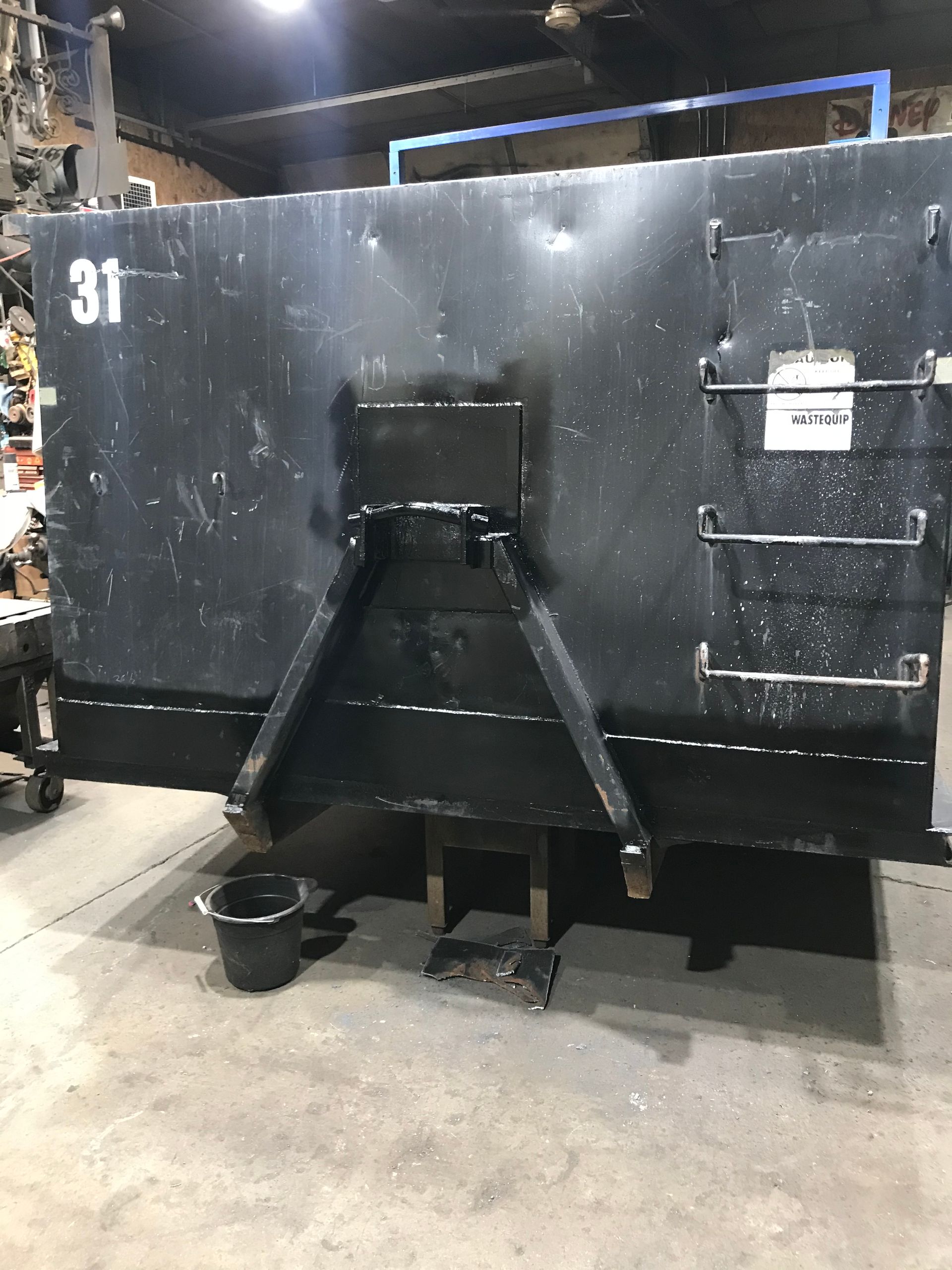 A black, industrial-style metal tank with the number 31, a ladder on the right, and a support frame, inside a shop.