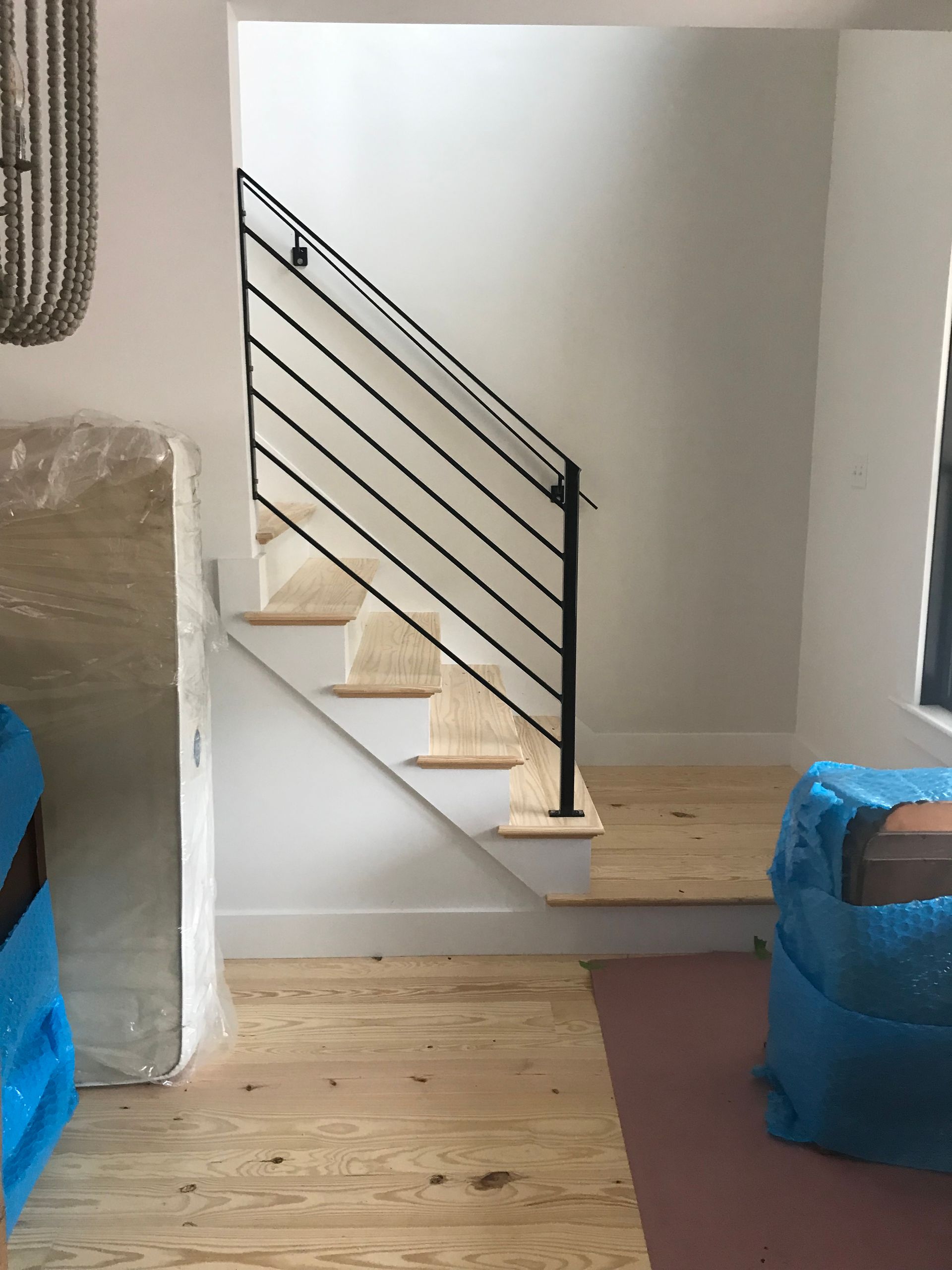 Interior view of a staircase featuring wooden steps, white risers, and a modern black metal horizontal railing.