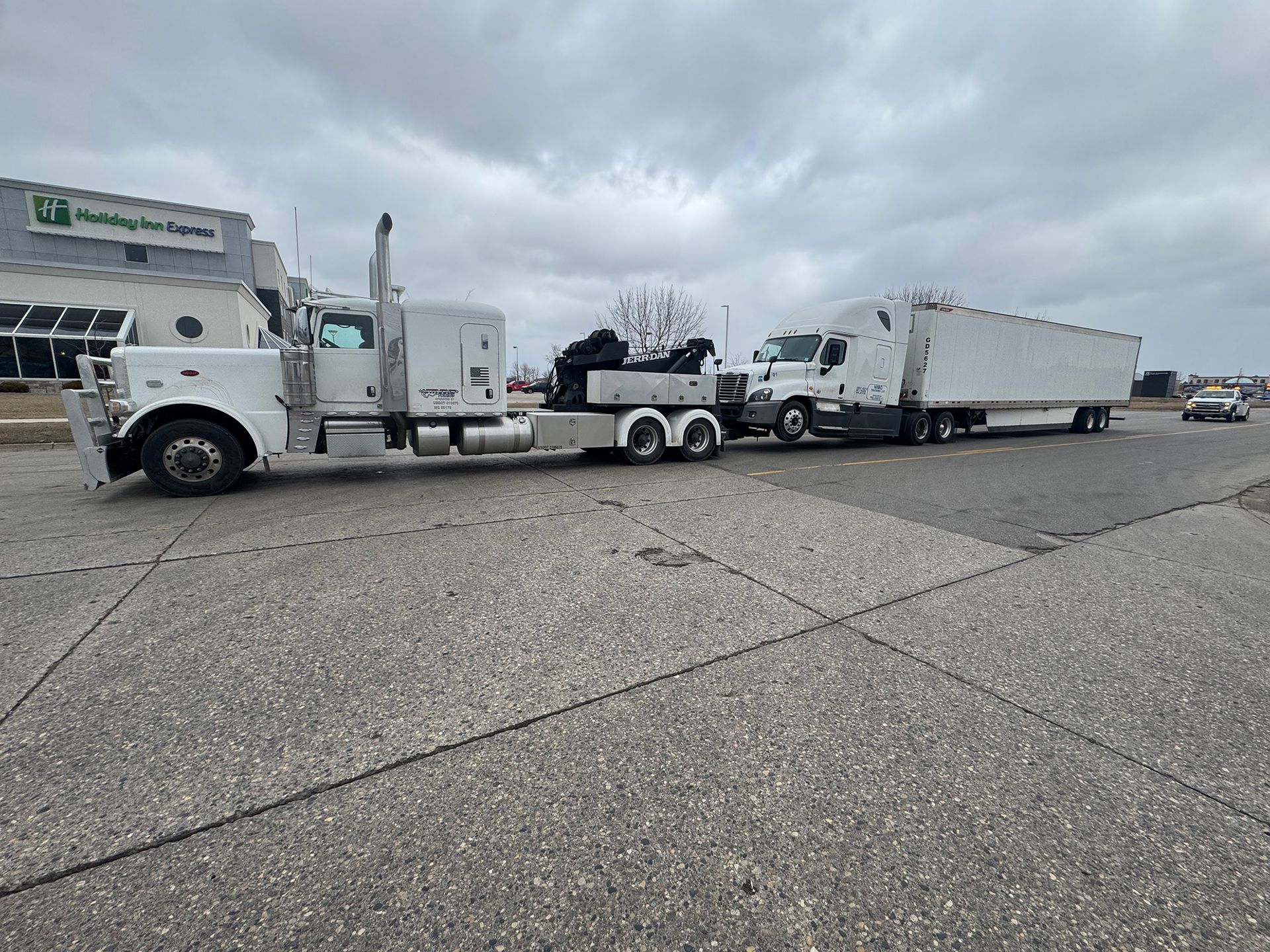 White semi truck towing a box trailer in a parking lot under cloudy skies