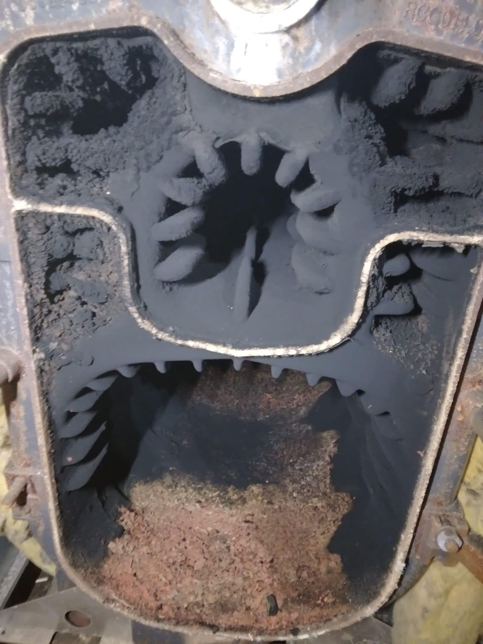 Close-up of a rusted mechanical gear assembly with dark metal cogs inside a worn housing.