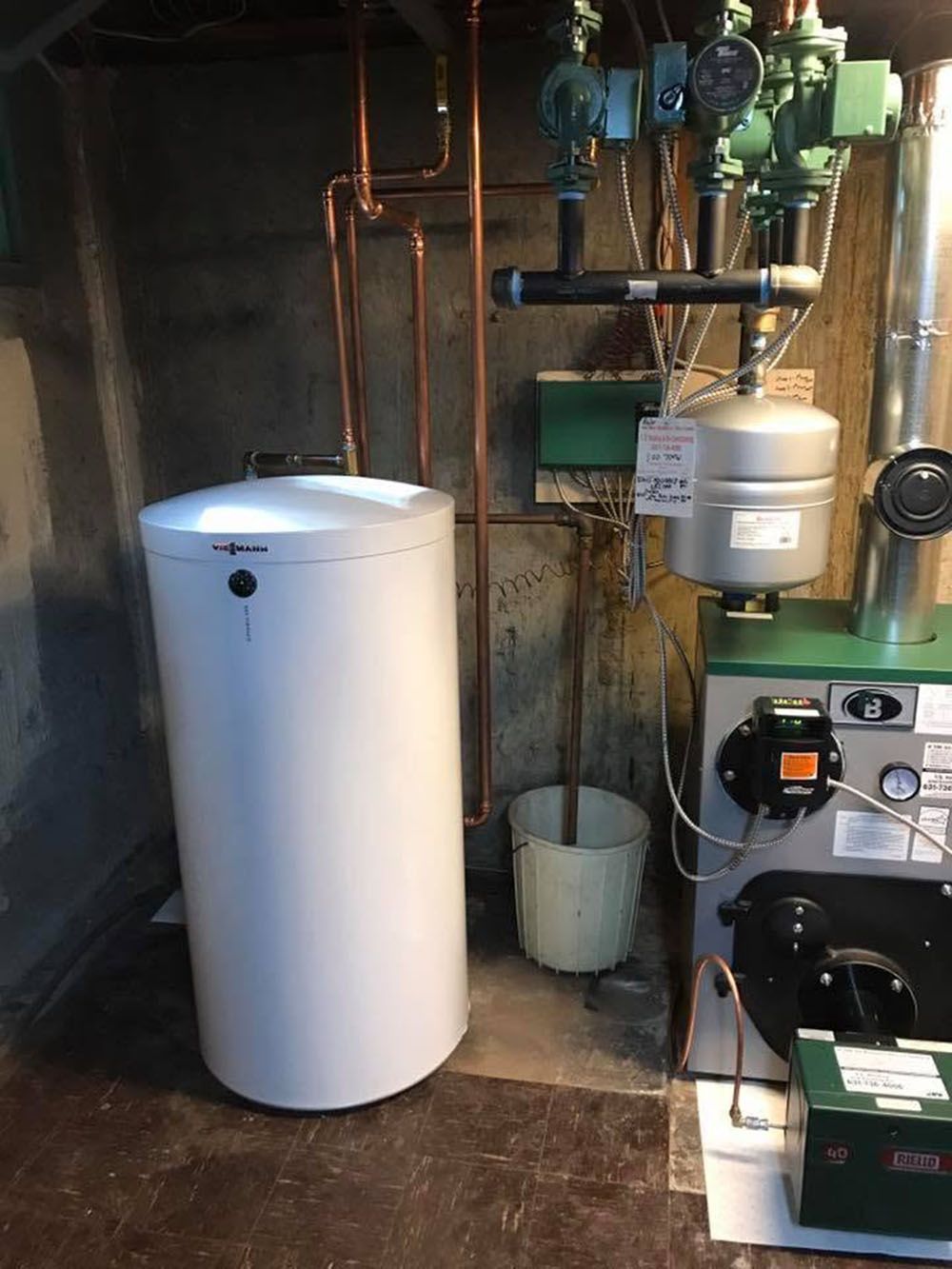 Basement utility area with a white water heater, plumbing pipes, and boiler equipment.