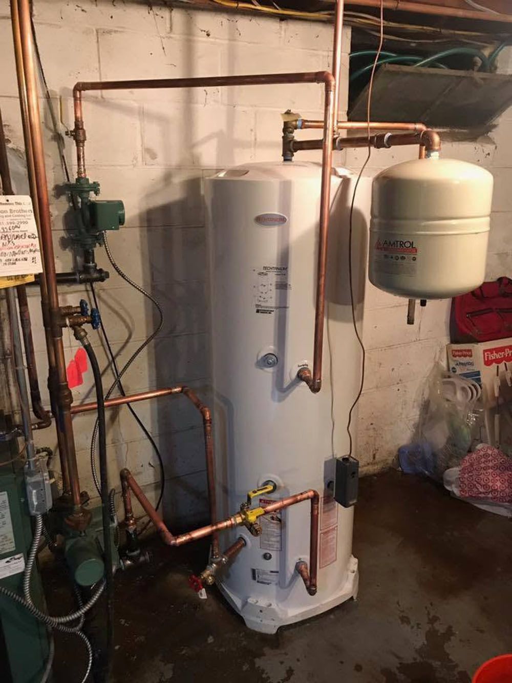 Water heater in a utility basement with copper pipes and a small expansion tank.
