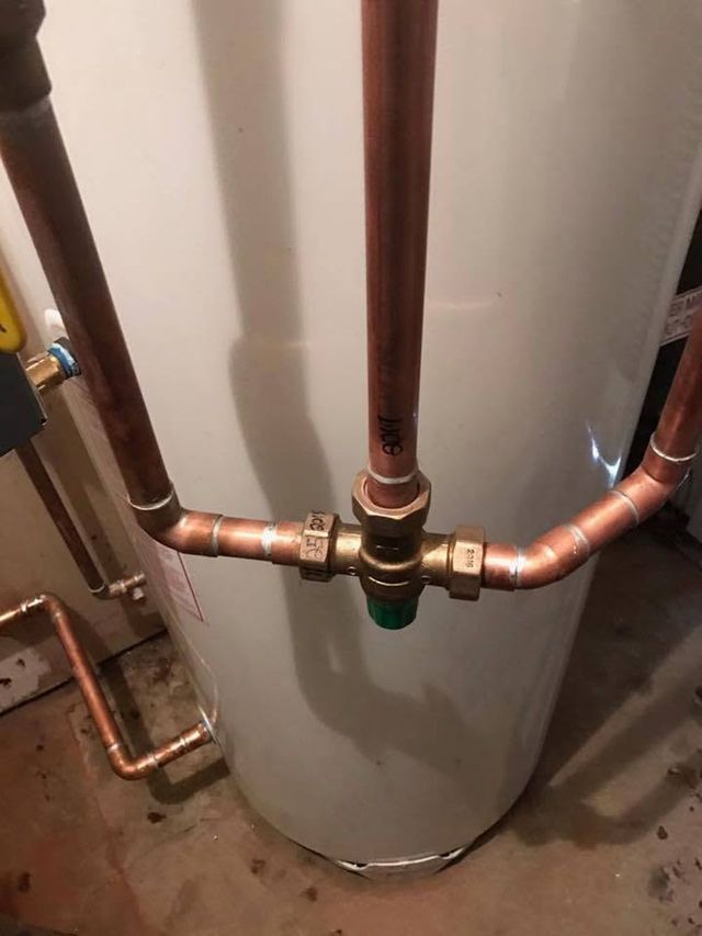 Copper plumbing pipes connected to a water heater in a utility room.