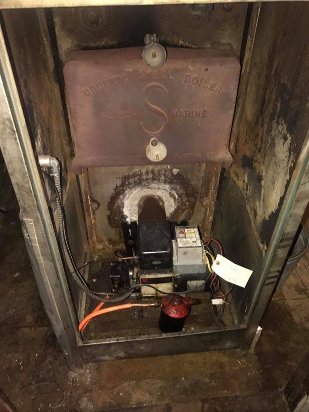Open metal boiler or furnace compartment with exposed wiring and motor components.