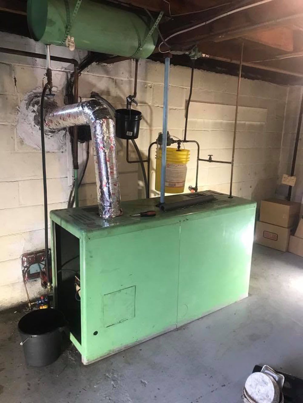Green industrial boiler with metal ducting in a basement utility room