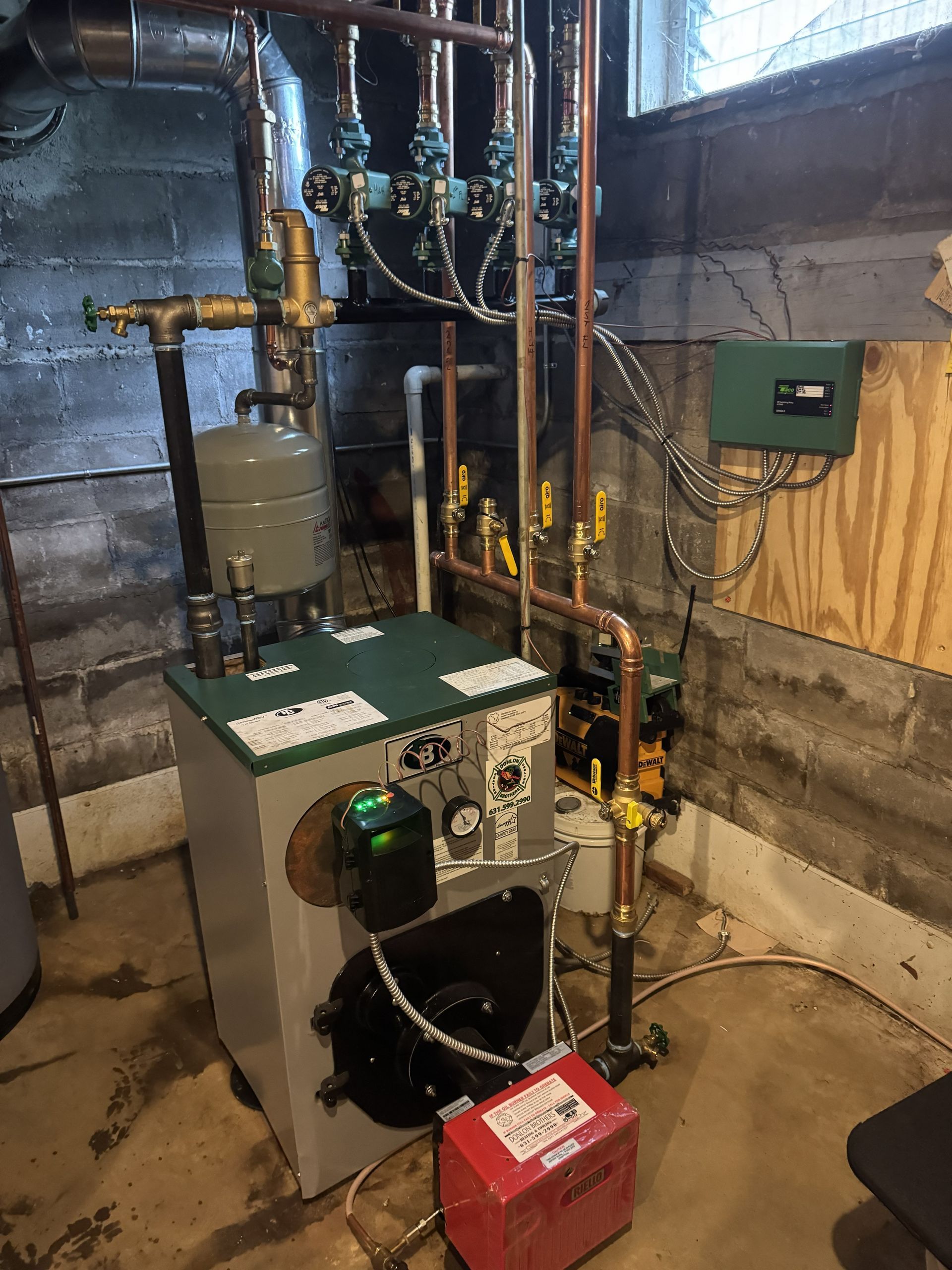 Basement utility room with furnace, water heater, exposed pipes, and electrical panel.