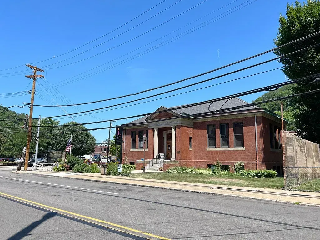 Red brick library building with front steps, street, power lines.