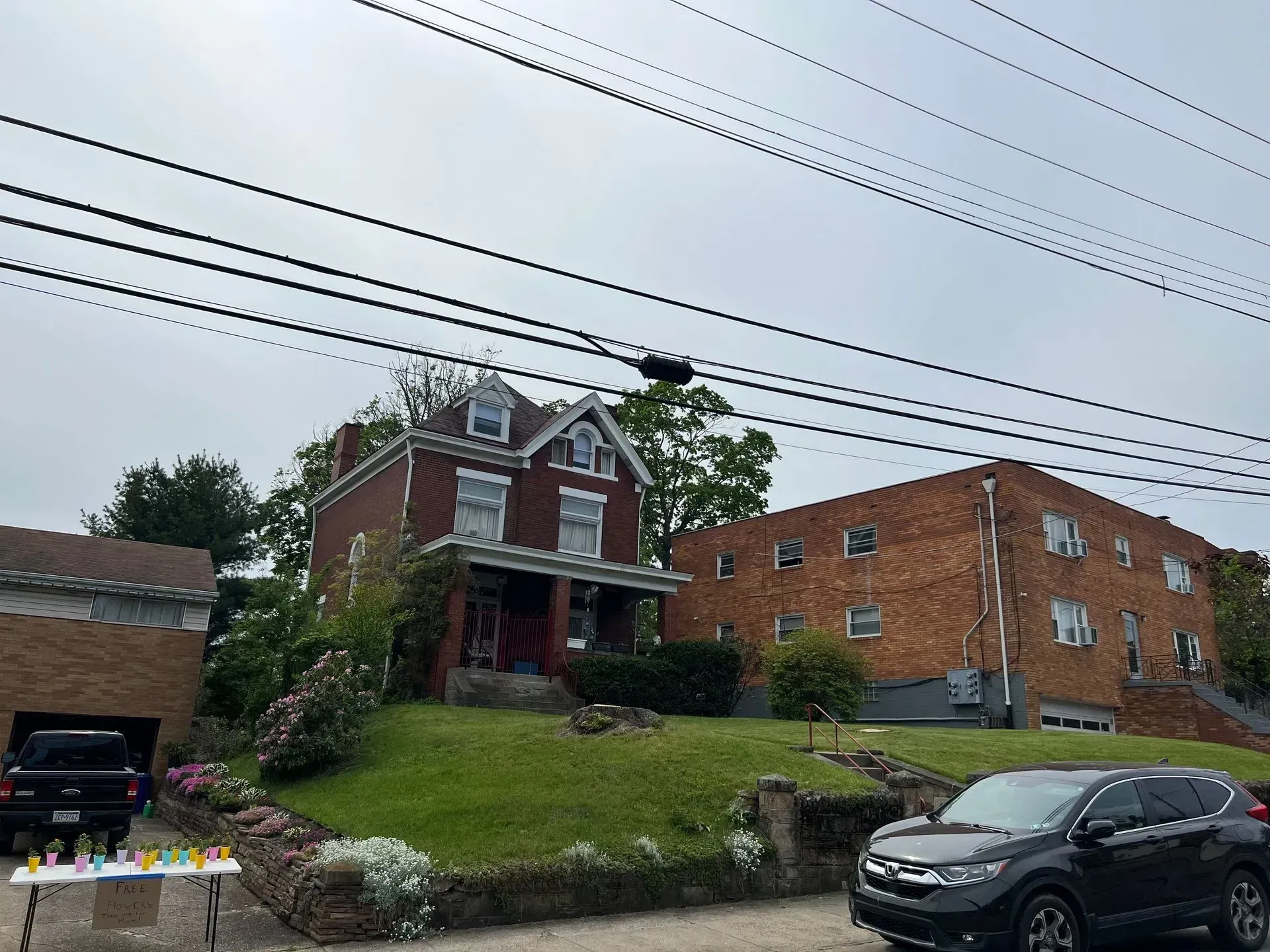 Brick house with small lawn, car parked in front, power lines overhead.