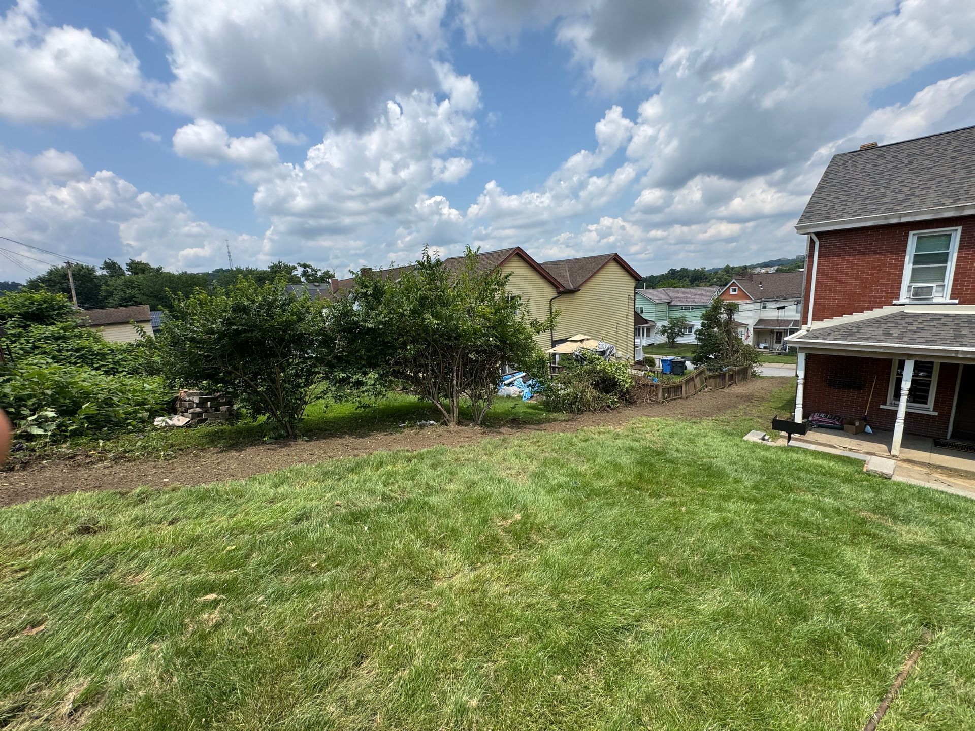 Backyard lawn overlooking neighboring houses under a cloudy sky