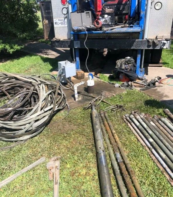 Utility truck with hoses and metal rods laid out on grass at a worksite