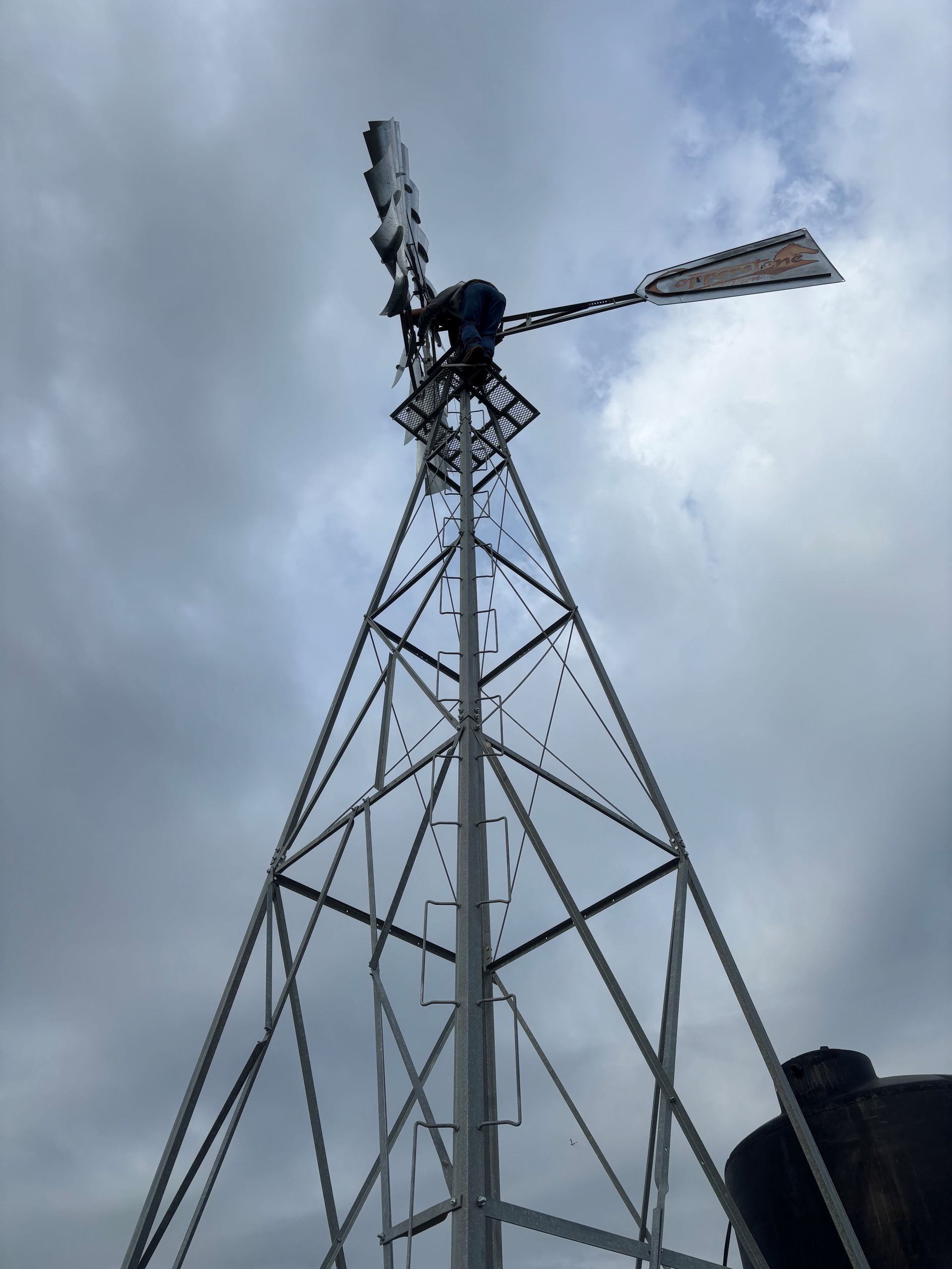 Tall metal windmill tower against a cloudy gray sky