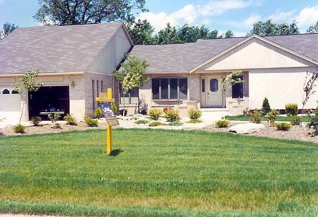 Suburban house with attached garage, front lawn, and landscaped yard under a clear sky