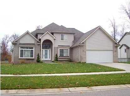 Suburban house with gray siding, front lawn, and two-car garage on a quiet street
