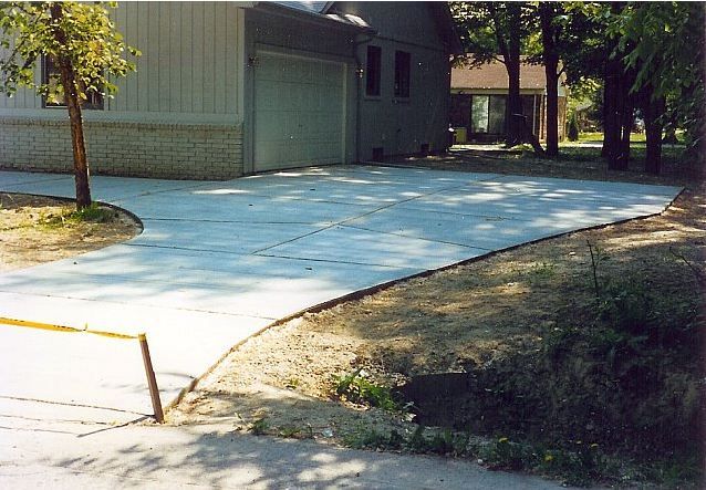 Concrete sidewalk beside a building and trees on a sunny day