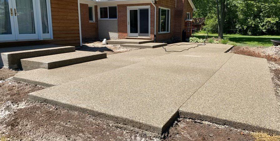 Cracked concrete patio leading to a house entry with steps and sliding glass door
