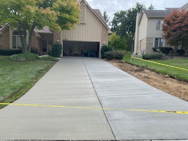 Residential driveway beside houses with a yellow tape barrier across the foreground