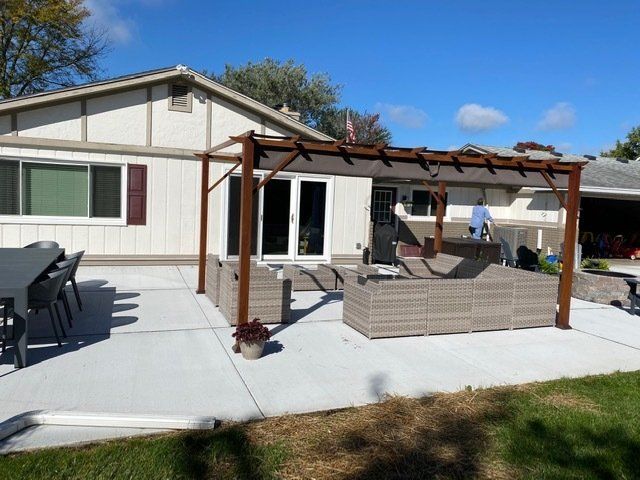 Backyard patio with a pergola, wicker sofa, grill, and outdoor dining set beside a house