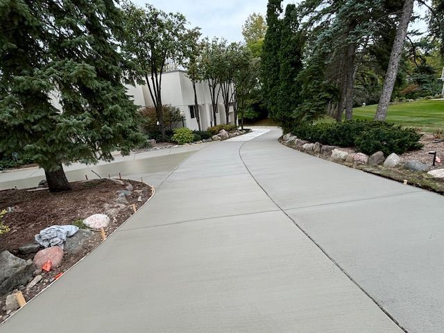Curving concrete sidewalk lined with trees and landscaping beside a building