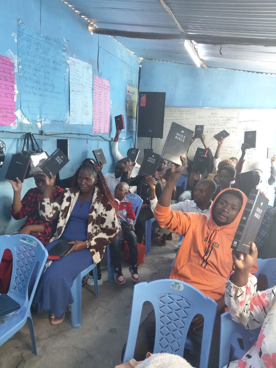 People in a blue room, holding up tablets. Some are smiling, others looking at the devices.