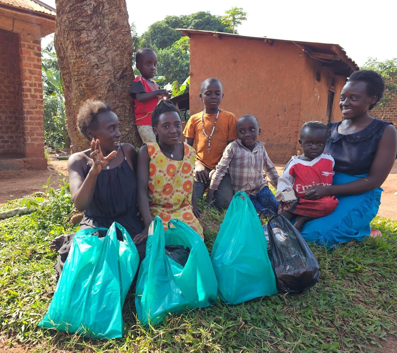 Group of people with bags, posing outdoors near a tree and buildings.