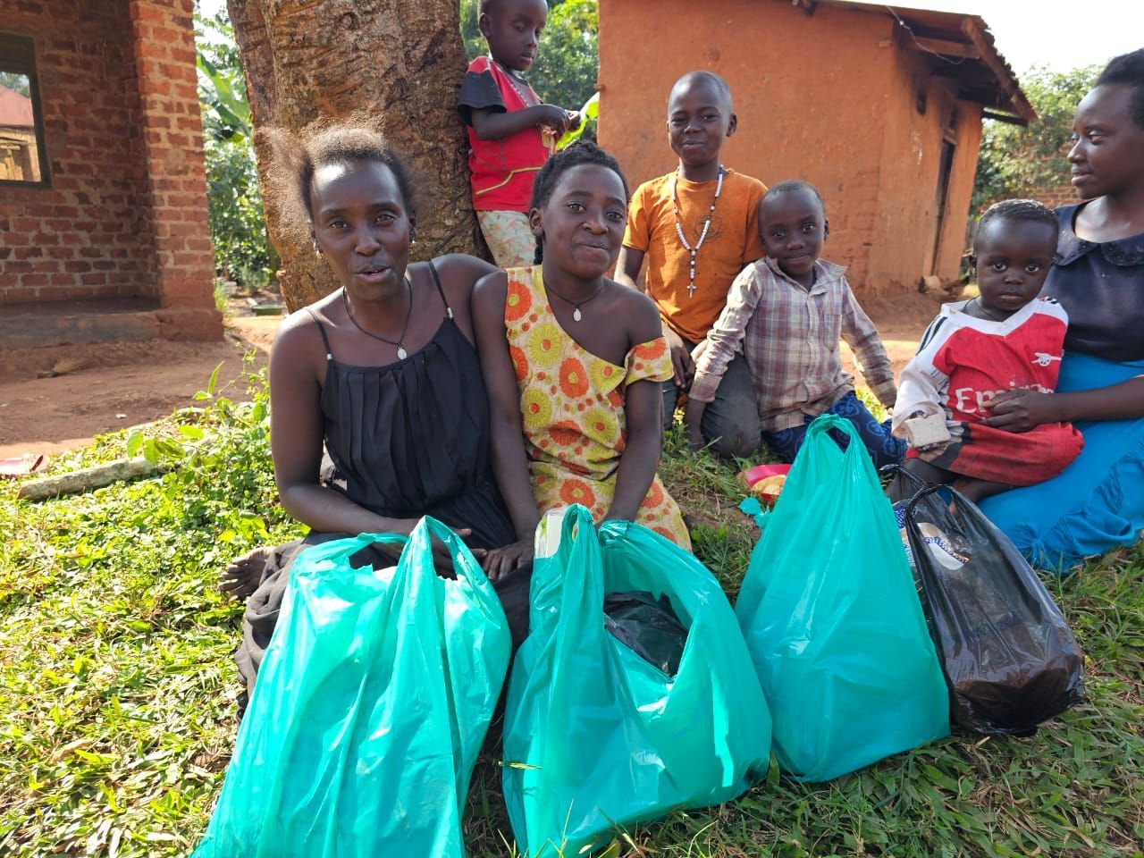 People sitting with bags of supplies outdoors in front of a building.
