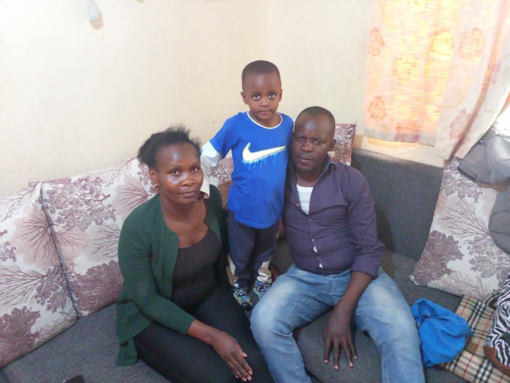 Family of three on a couch: mother, child in blue, and father in purple shirt.