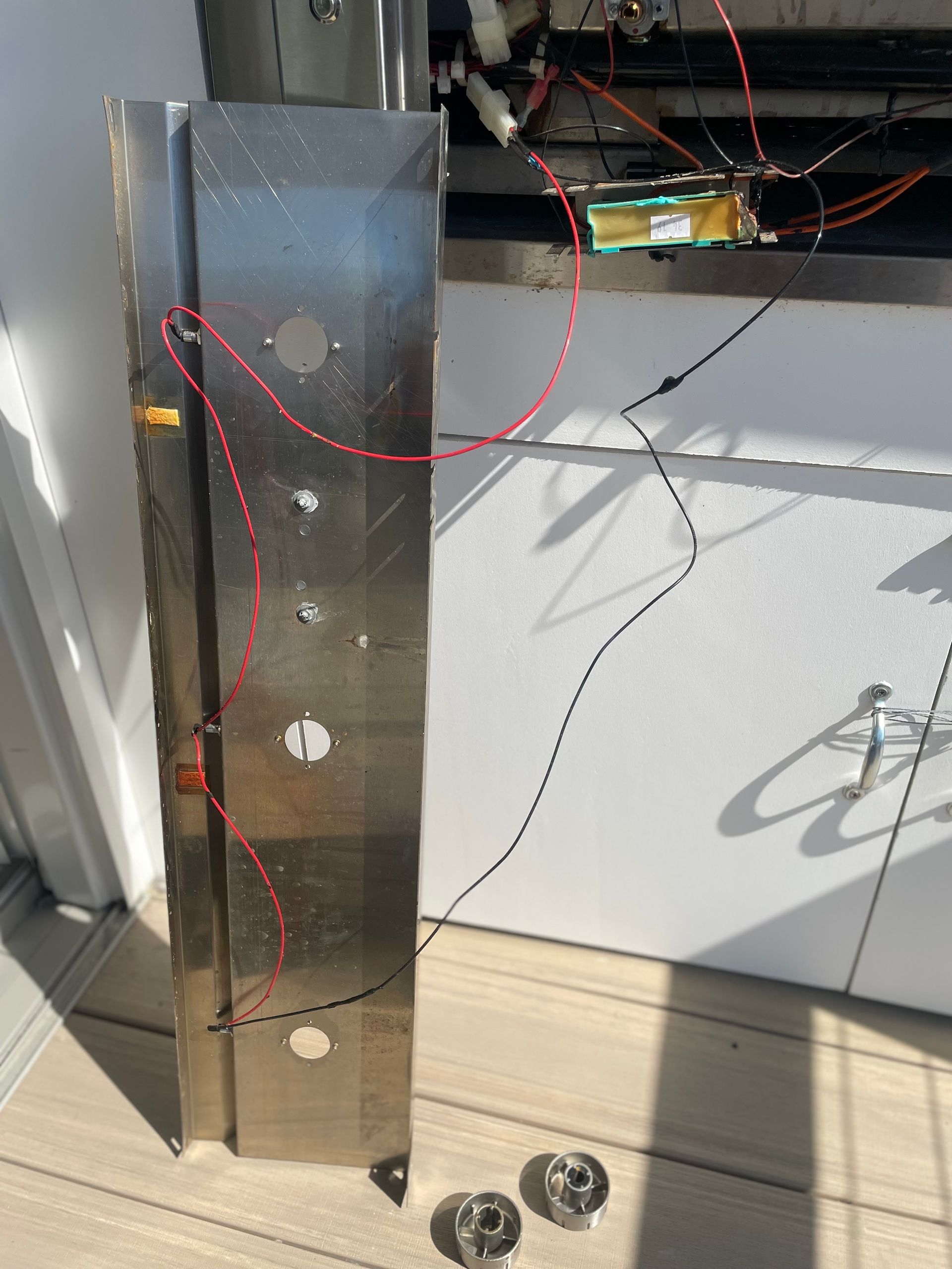 Stainless steel elevator button panel with wires, holes, and two screws.