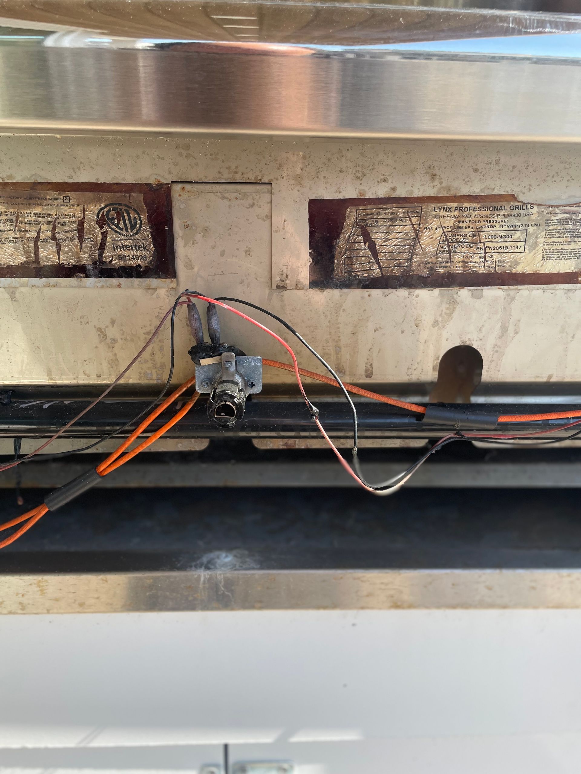 Metal panel with wiring and a switch. Two rectangular openings show burnt material.